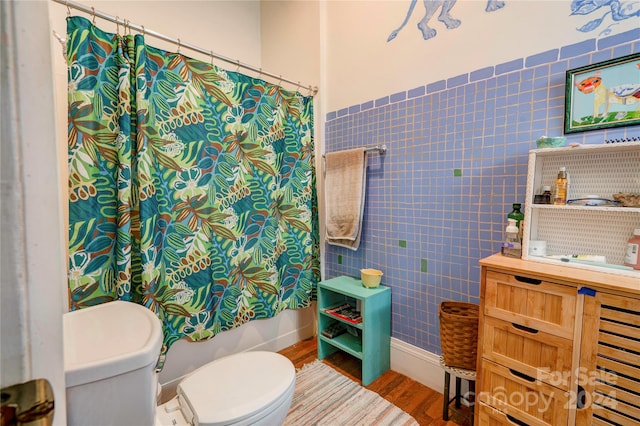 bathroom with hardwood / wood-style floors, shower / bathtub combination with curtain, tile walls, and toilet