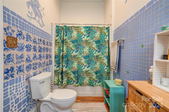 bathroom with hardwood / wood-style floors, shower / tub combo, toilet, and tile walls