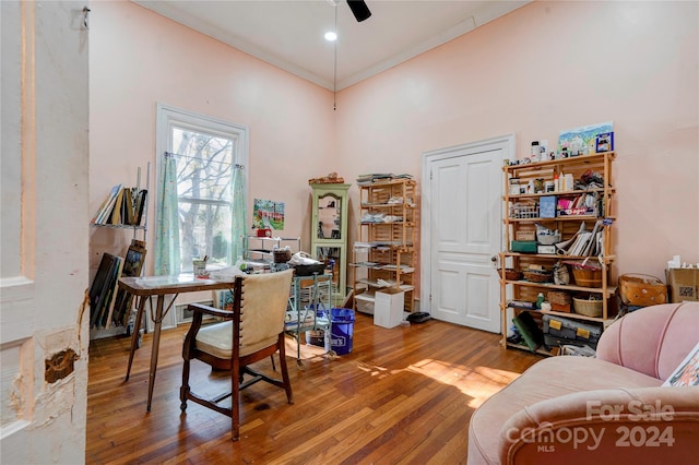 office with hardwood / wood-style floors, ceiling fan, crown molding, and a high ceiling