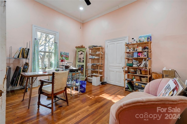 office featuring ceiling fan, wood-type flooring, crown molding, and a high ceiling