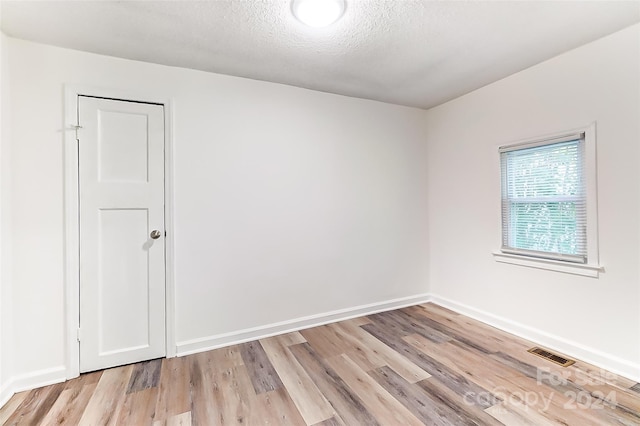 spare room with light hardwood / wood-style floors and a textured ceiling