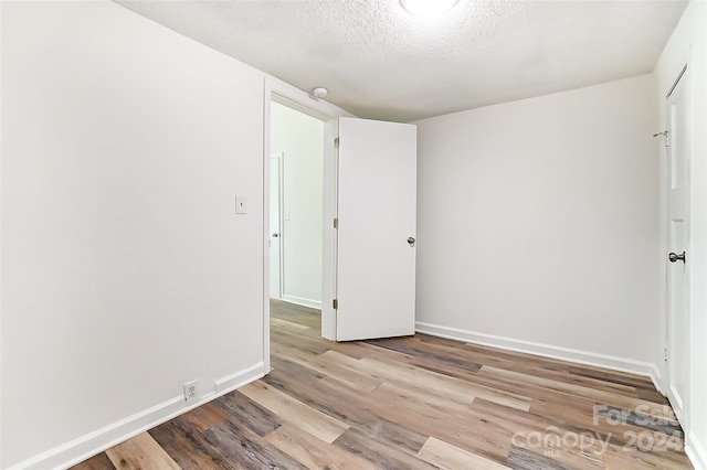 spare room with a textured ceiling and light hardwood / wood-style flooring