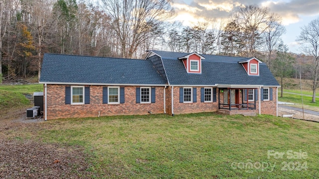 cape cod home with a yard and central air condition unit