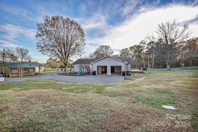 view of yard featuring a playground, a garage, and a storage shed