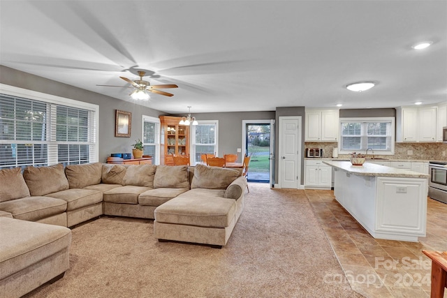 living room with sink, light tile patterned flooring, and ceiling fan with notable chandelier