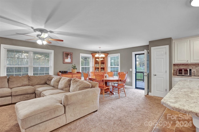 carpeted living room featuring ceiling fan with notable chandelier