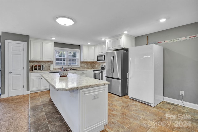 kitchen with a kitchen island, white cabinets, and appliances with stainless steel finishes