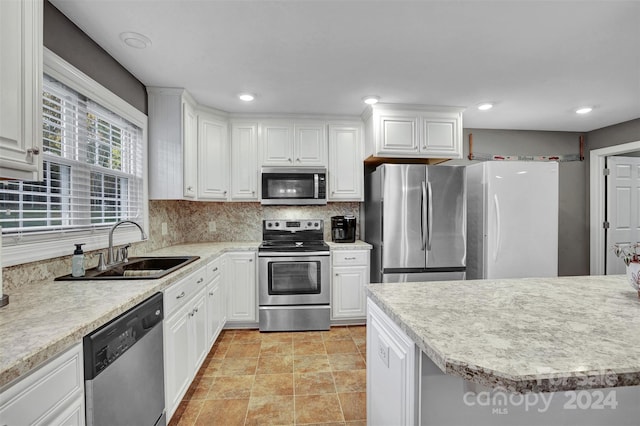 kitchen with backsplash, white cabinetry, sink, and appliances with stainless steel finishes