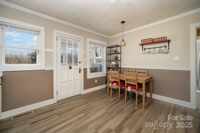 dining room with wood-type flooring, a textured ceiling, and crown molding