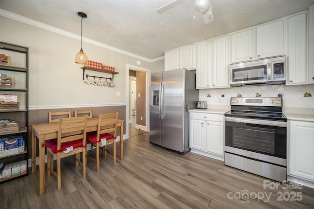 kitchen with white cabinetry, light hardwood / wood-style flooring, appliances with stainless steel finishes, pendant lighting, and decorative backsplash