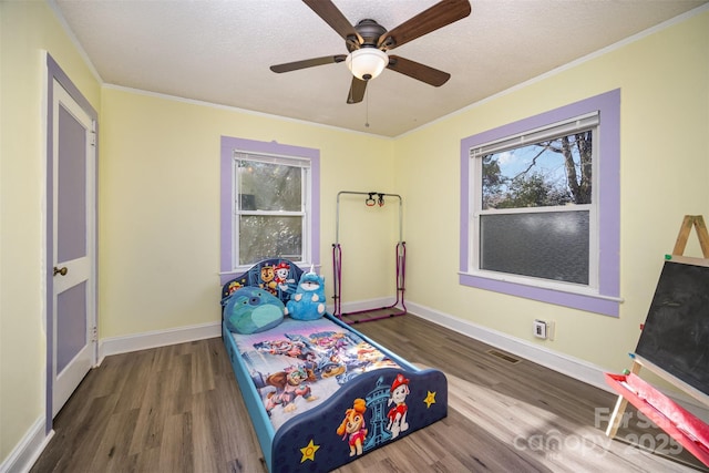 bedroom with ornamental molding, dark wood-type flooring, ceiling fan, and a textured ceiling