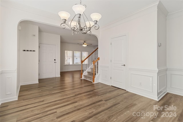 interior space with ornamental molding, ceiling fan with notable chandelier, and dark wood-type flooring