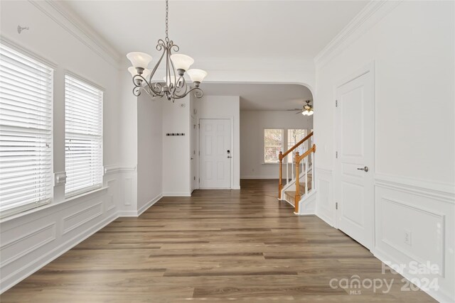 dining space with dark hardwood / wood-style flooring, ceiling fan with notable chandelier, and ornamental molding