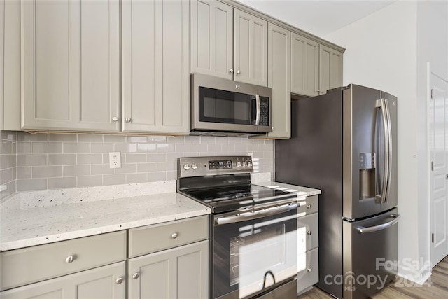 kitchen featuring light stone countertops, stainless steel appliances, tasteful backsplash, and hardwood / wood-style flooring