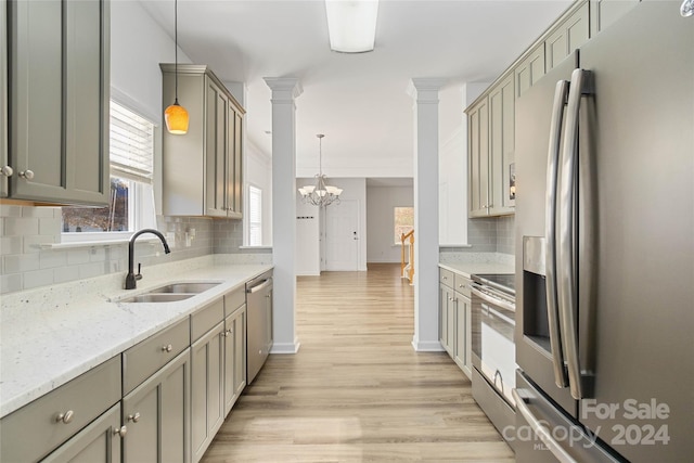 kitchen with sink, tasteful backsplash, light hardwood / wood-style flooring, decorative light fixtures, and appliances with stainless steel finishes