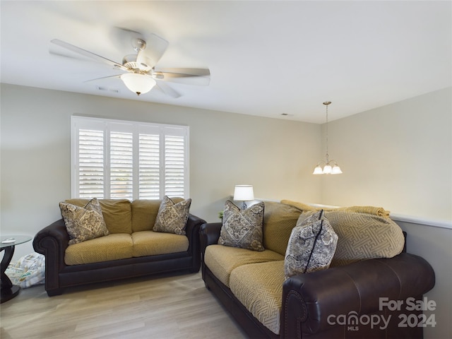 living room featuring ceiling fan with notable chandelier and light wood-type flooring