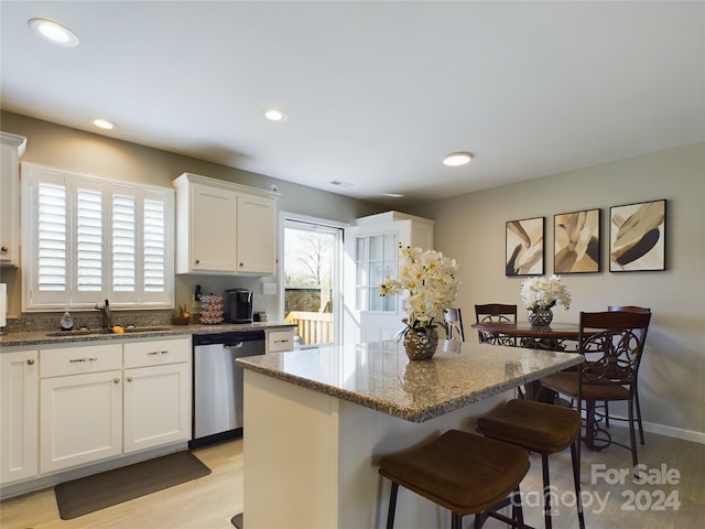 kitchen featuring dishwasher, white cabinets, light hardwood / wood-style flooring, and dark stone counters