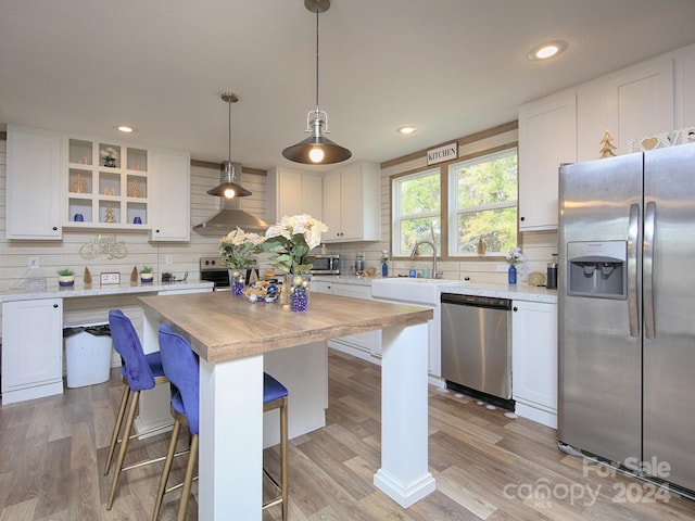 kitchen featuring white cabinets, hanging light fixtures, and appliances with stainless steel finishes