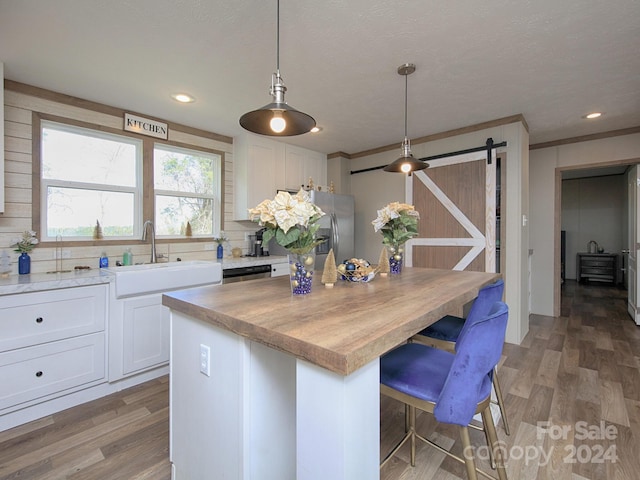 kitchen with decorative backsplash, a barn door, white cabinets, a center island, and hanging light fixtures