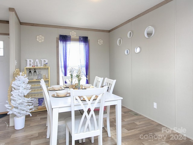 dining area with ornamental molding and light hardwood / wood-style flooring