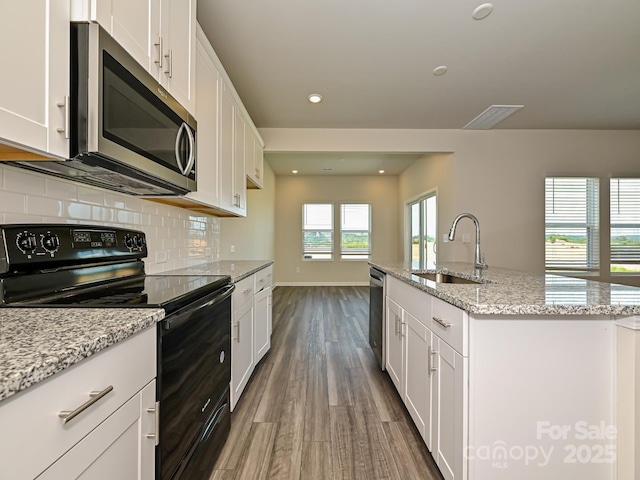 kitchen with stainless steel appliances, white cabinetry, a center island with sink, and sink