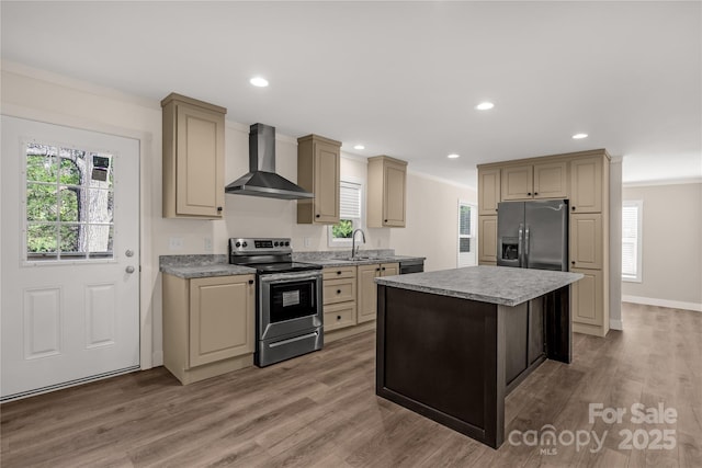 kitchen with a center island, cream cabinets, wall chimney range hood, sink, and stainless steel appliances