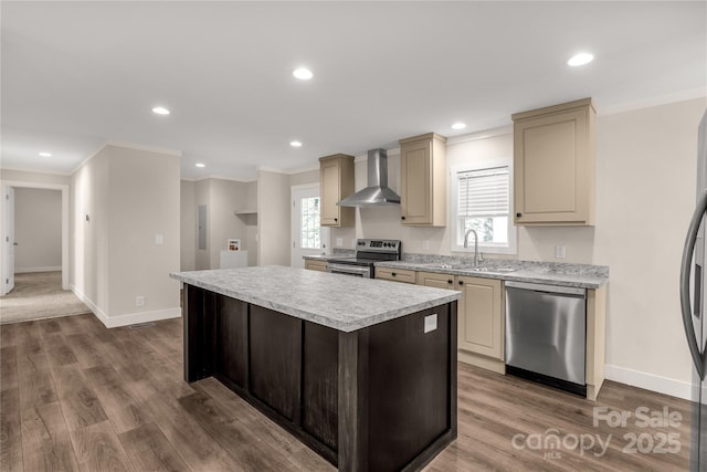 kitchen with sink, wall chimney exhaust hood, cream cabinets, a kitchen island, and appliances with stainless steel finishes