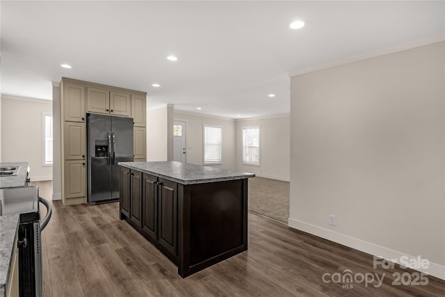 kitchen with appliances with stainless steel finishes, a center island, crown molding, and cream cabinets