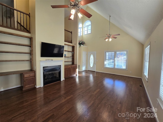 unfurnished living room featuring a wealth of natural light, high vaulted ceiling, dark wood-type flooring, and a textured ceiling