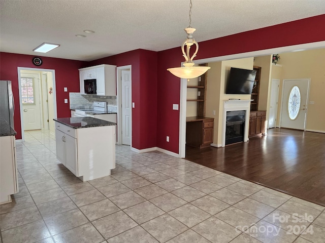 kitchen with white range with electric stovetop, light wood-type flooring, a textured ceiling, decorative light fixtures, and white cabinetry