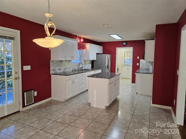 kitchen with white cabinets, stainless steel fridge, decorative backsplash, and a kitchen island