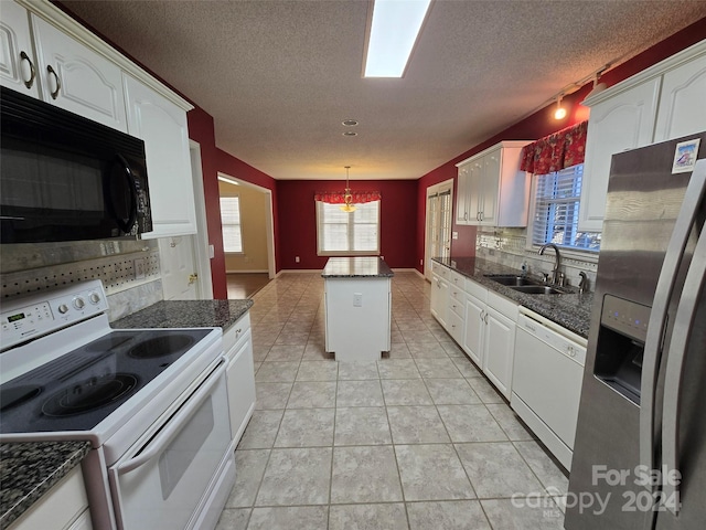 kitchen featuring plenty of natural light, sink, a kitchen island, and white appliances