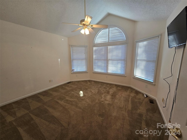 spare room featuring dark colored carpet, a textured ceiling, ceiling fan, and lofted ceiling