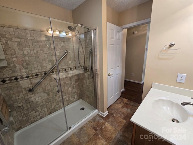 bathroom with a textured ceiling, vanity, and an enclosed shower