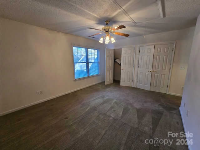 unfurnished bedroom featuring ceiling fan, a textured ceiling, and dark colored carpet