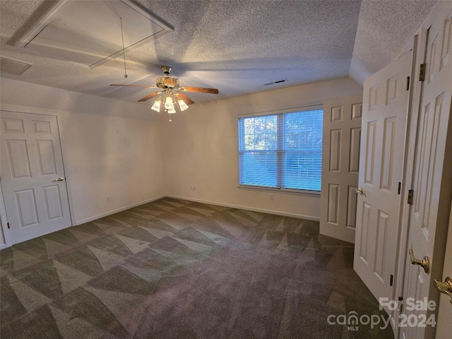 unfurnished bedroom with vaulted ceiling, ceiling fan, a textured ceiling, and dark colored carpet