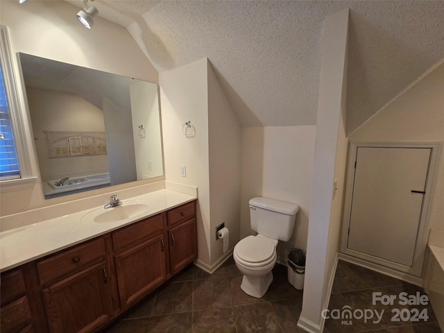 bathroom with vanity, a textured ceiling, tile patterned floors, and lofted ceiling