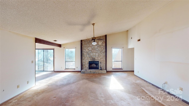 unfurnished living room with a stone fireplace, ceiling fan, carpet, and a healthy amount of sunlight