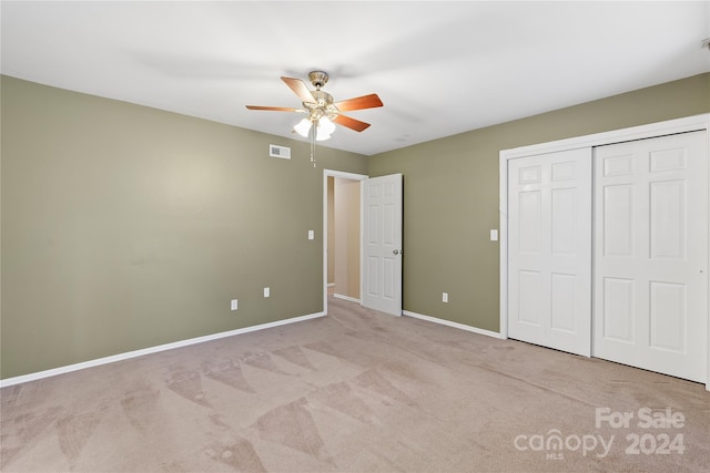 unfurnished bedroom featuring ceiling fan, a closet, and light carpet