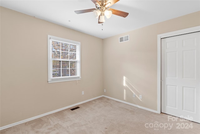 unfurnished bedroom featuring light carpet, a closet, and ceiling fan