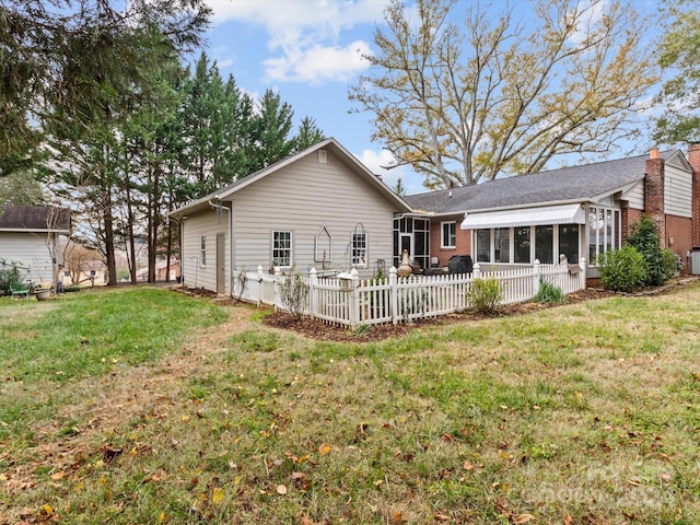 back of house with a sunroom and a lawn