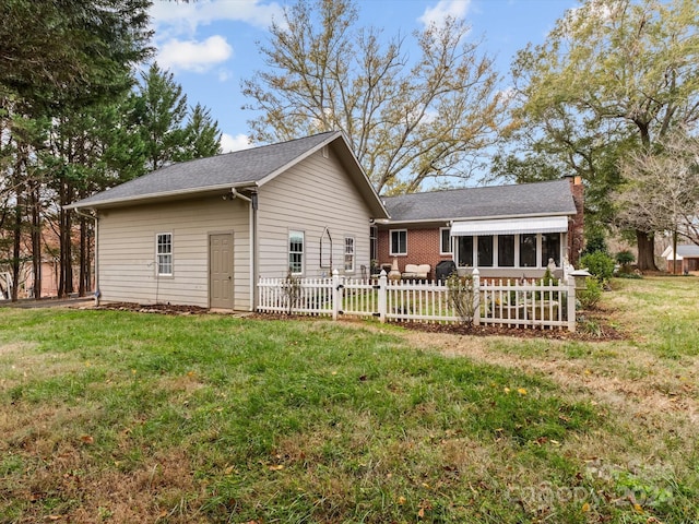 rear view of house featuring a sunroom and a yard