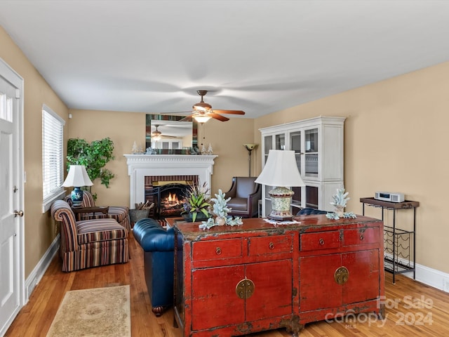 living room featuring light hardwood / wood-style floors, a brick fireplace, and ceiling fan