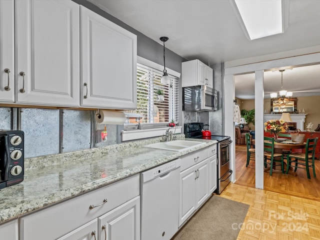 kitchen featuring appliances with stainless steel finishes, sink, decorative light fixtures, a notable chandelier, and white cabinets