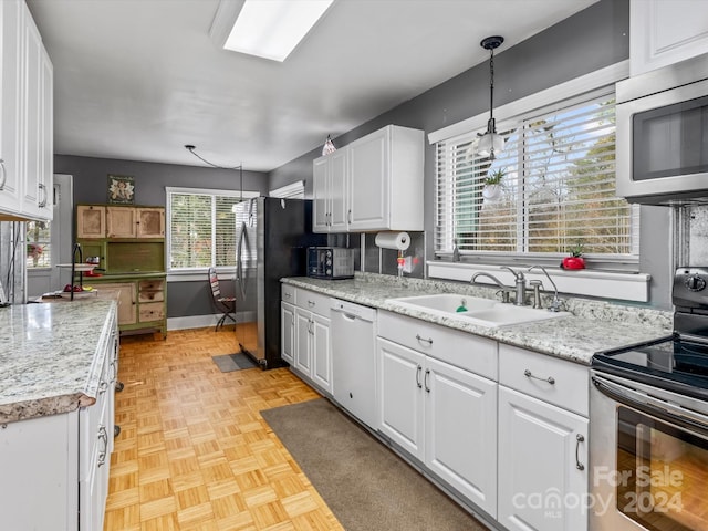 kitchen featuring sink, white cabinetry, hanging light fixtures, and stainless steel appliances