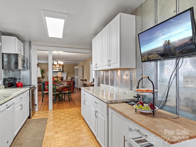 kitchen featuring white cabinets, appliances with stainless steel finishes, a chandelier, and butcher block counters