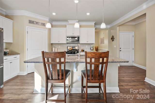 kitchen featuring a kitchen bar, a kitchen island with sink, hanging light fixtures, and stainless steel appliances