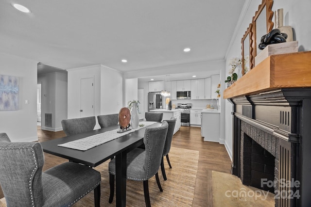 dining room featuring hardwood / wood-style flooring, ornamental molding, and sink