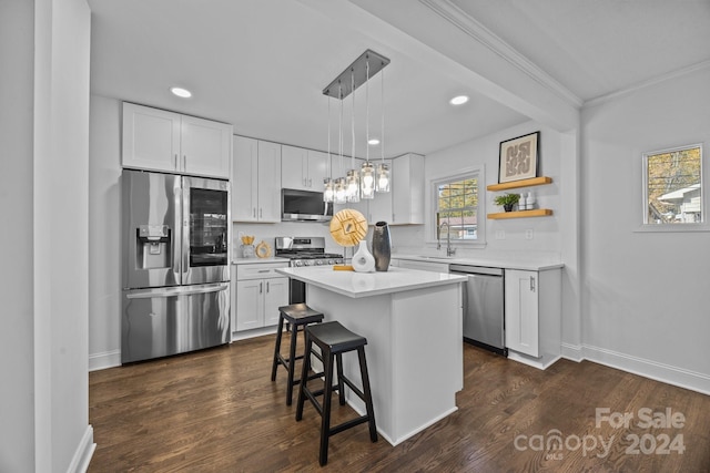 kitchen with white cabinets, appliances with stainless steel finishes, a center island, and hanging light fixtures