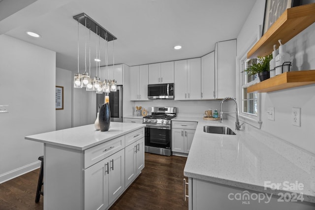 kitchen with white cabinetry, sink, stainless steel appliances, dark hardwood / wood-style floors, and a kitchen island